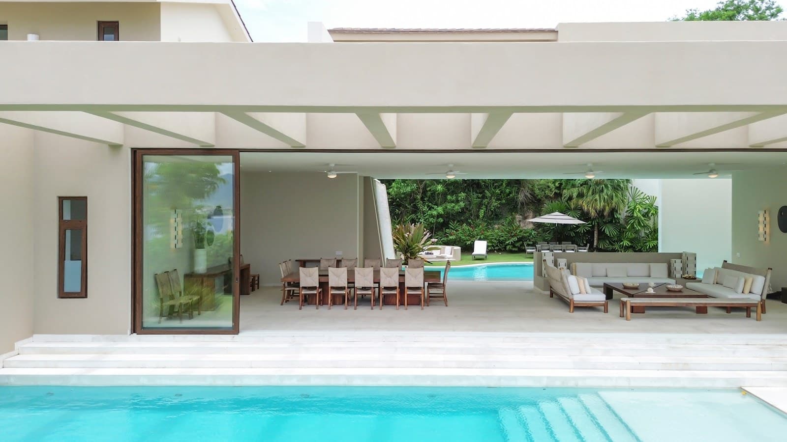 Modern tropical retreat featuring indoor-outdoor living spaces with seamless pool access and lush garden surroundings—your private sanctuary for relaxation and entertaining.