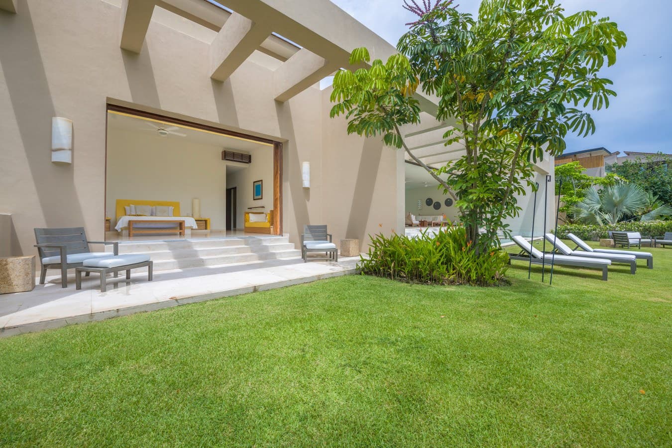 Your private escape opens to lush green lawns and sun-dappled loungers, where tropical breezes and tranquil garden views invite effortless relaxation.