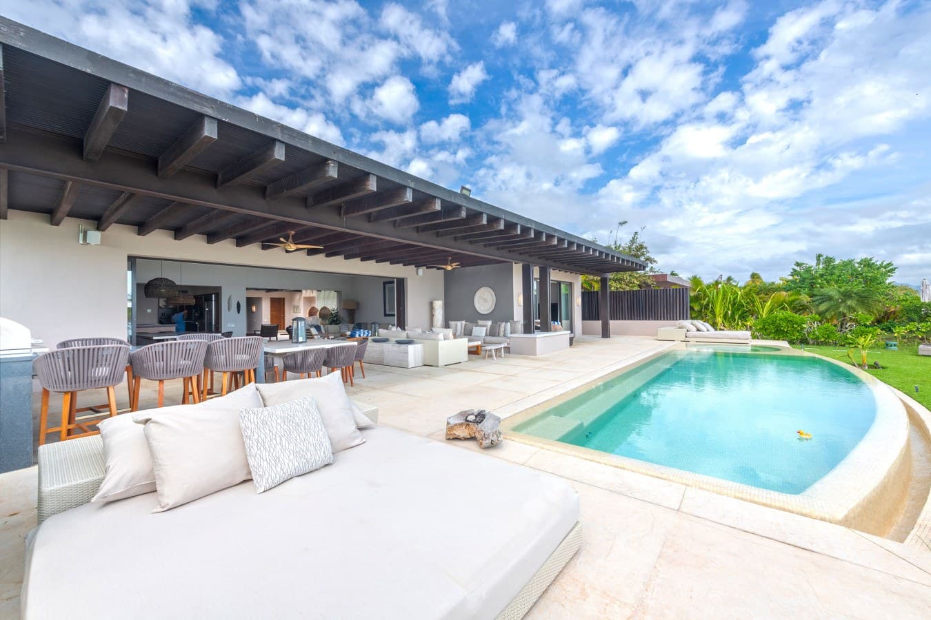 Picture yourself lounging by your private pool under the warm tropical sky, with plush outdoor seating and a shaded pergola just steps away. Your open-air retreat blends seamlessly with lush gardens, inviting you to relax in style.