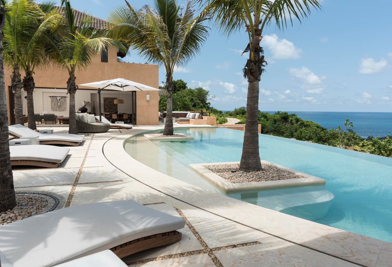 Soak in the stunning infinity pool with palm trees rising from crystal-clear waters while the ocean stretches endlessly beyond—your own slice of tropical paradise awaits.