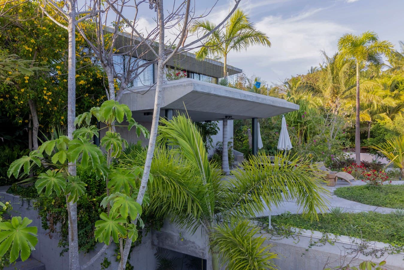 Modern architectural retreat elevated among tropical palms and lush gardens, blending contemporary design with natural beauty for a distinctive island getaway.