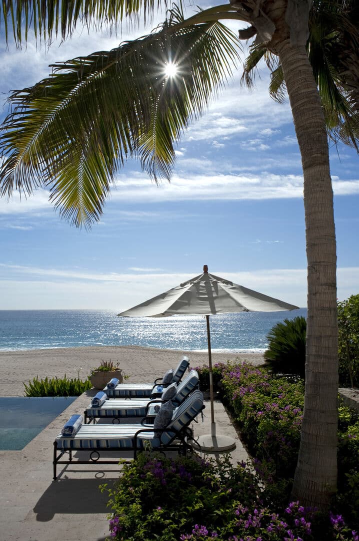Chaise lounges and patio umbrella by the pool with beautiful ocean views