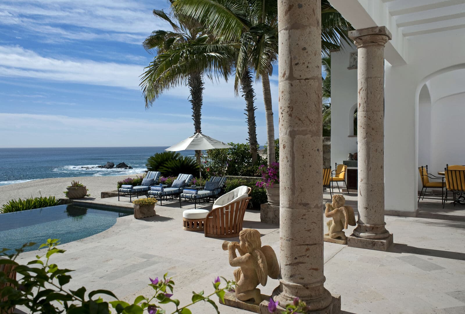 Outdoor furniture, chaise lounges, patio umbrella, and palm trees by the pool