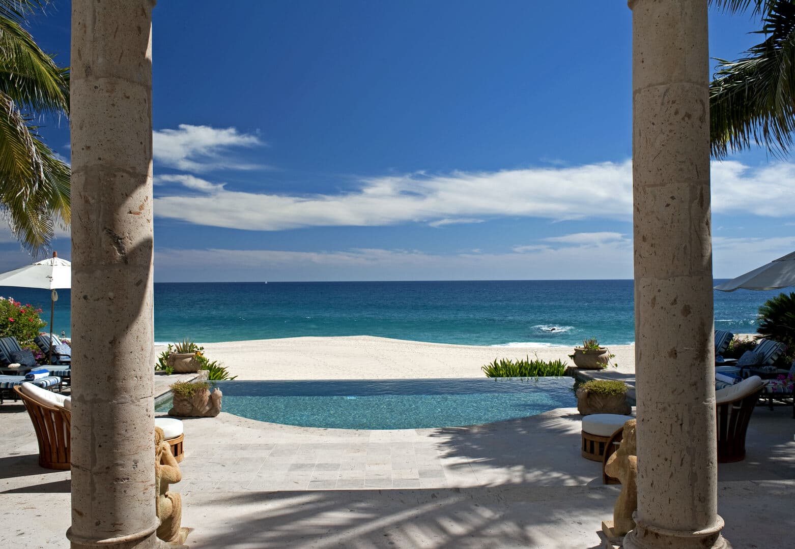 Infinity pool with sun deck, chaise lounges, and ocean view
