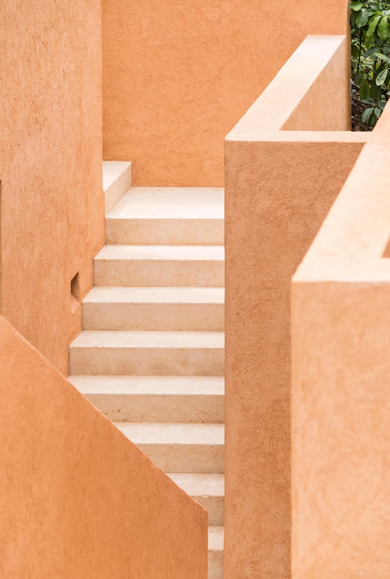 Sunlit terracotta stairway framed by warm stucco walls, showcasing the property's architectural charm and inviting arrival experience.