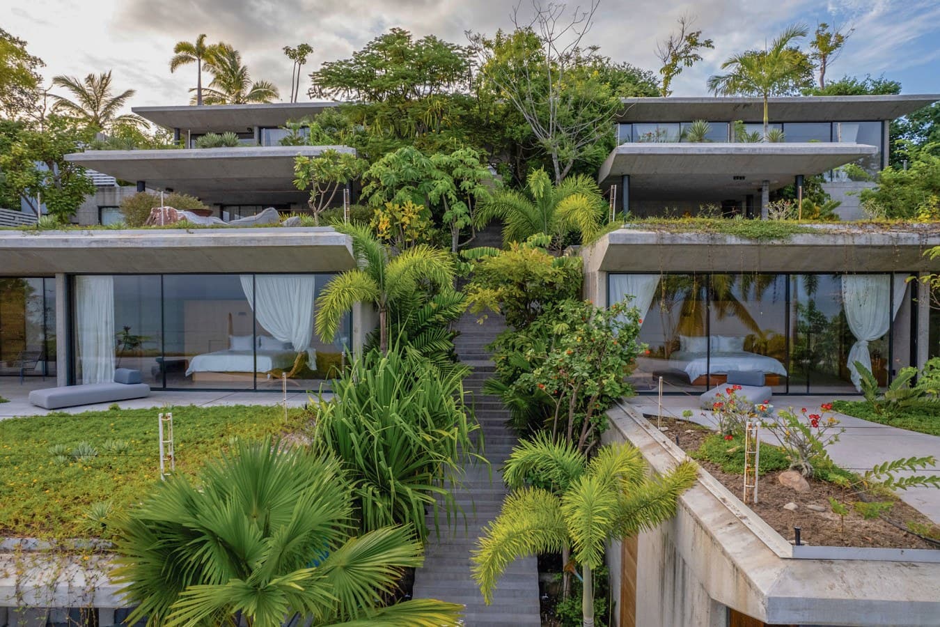 Contemporary architectural design with lush tropical landscaping on terraced levels overlooking a verdant hillside setting.