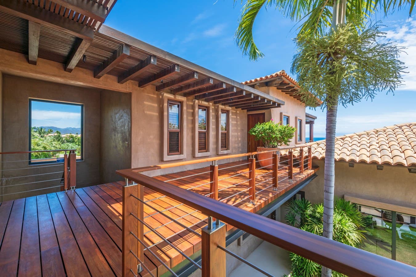 Step onto your private terrace, where polished wood decking and sleek cable railings frame sweeping tropical vistas. Lush palms sway overhead as you soak in the peaceful ambiance and breathtaking coastal scenery.