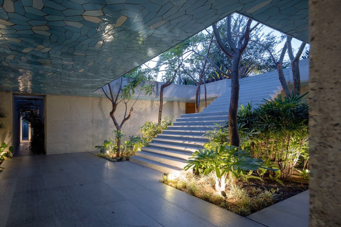 This distinctive property entrance features a stunning mosaic ceiling above an open-air courtyard with natural trees and tropical greenery, creating a serene welcome to your stay.