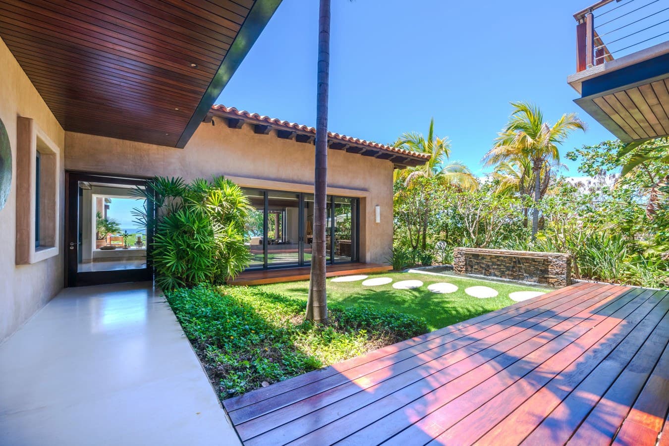 A private courtyard with lush tropical landscaping, sunny pathways, and warm wood details creates an inviting retreat within the property.