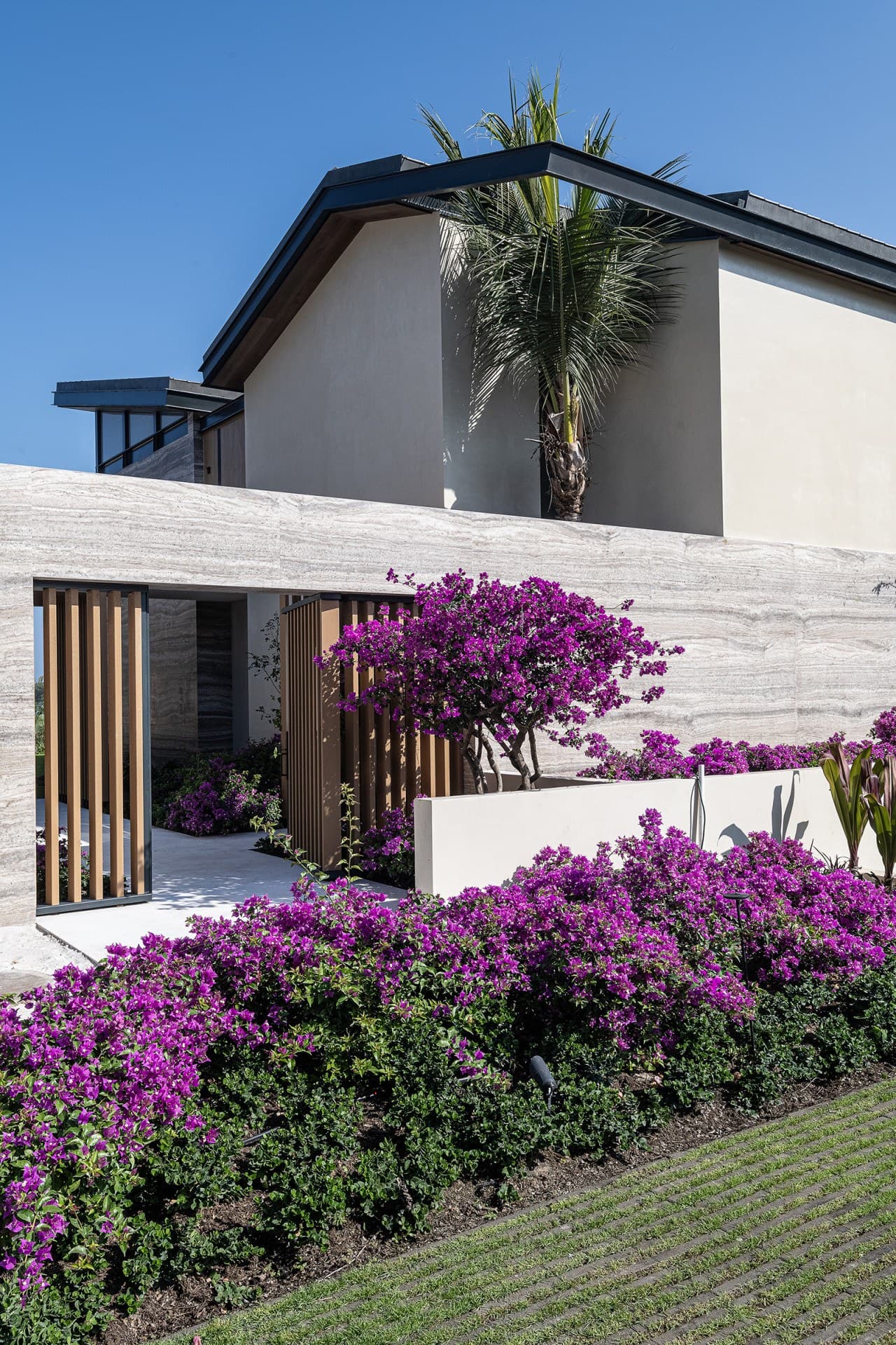 Modern architecture meets tropical elegance at this distinctive property, where vibrant bougainvillea blooms frame the contemporary exterior and welcoming entrance.