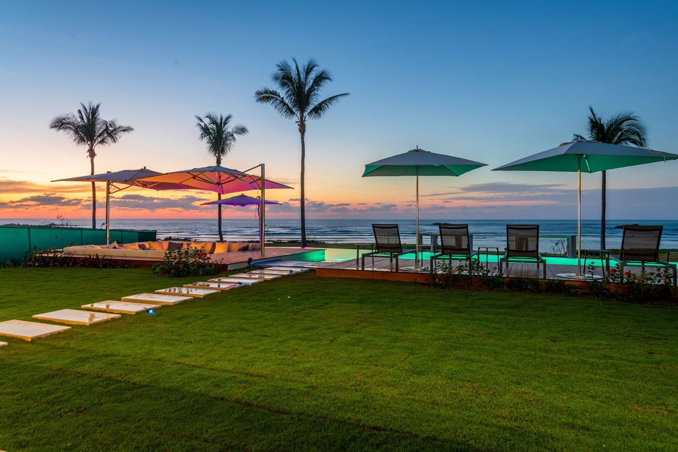 This stunning beachfront property features a sparkling pool, lush tropical landscaping, and breathtaking ocean views, perfect for relaxing evenings under swaying palm trees.