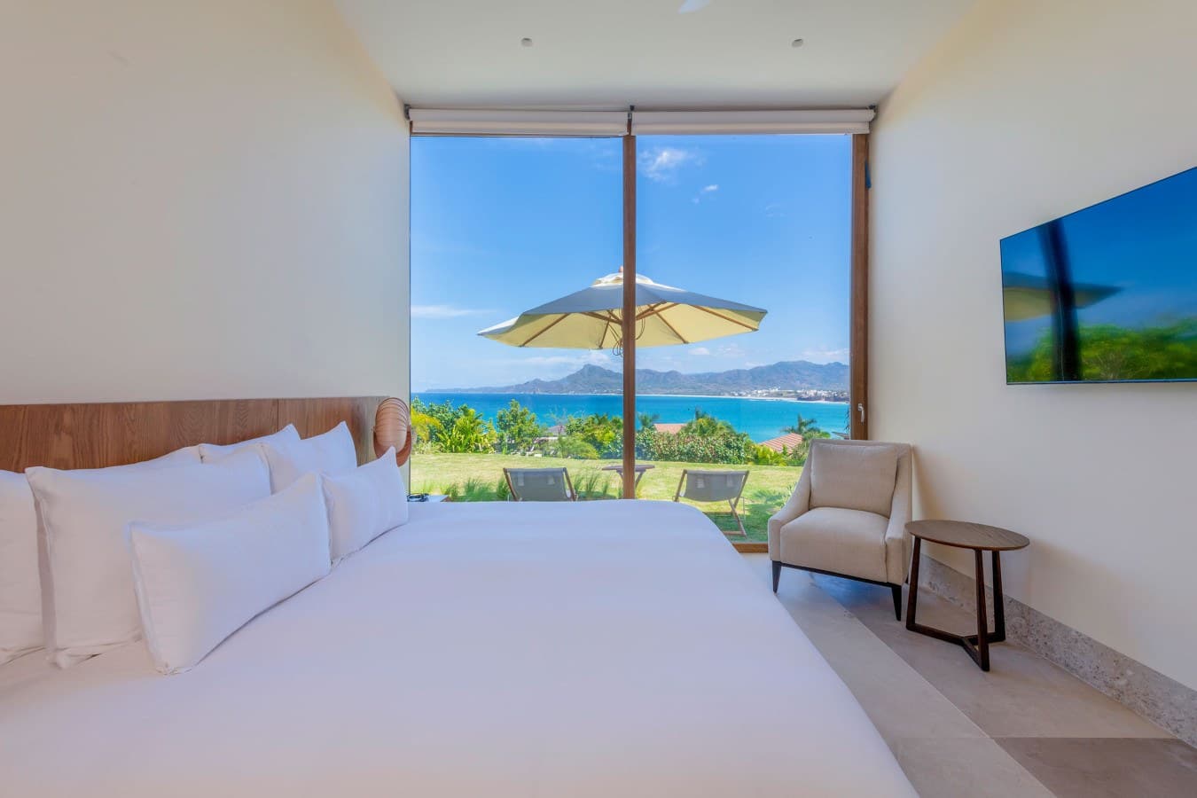 Wake up to breathtaking ocean and mountain views framed by floor-to-ceiling windows. Your plush bed and cozy seating area await, while the garden terrace beckons just beyond your private retreat.