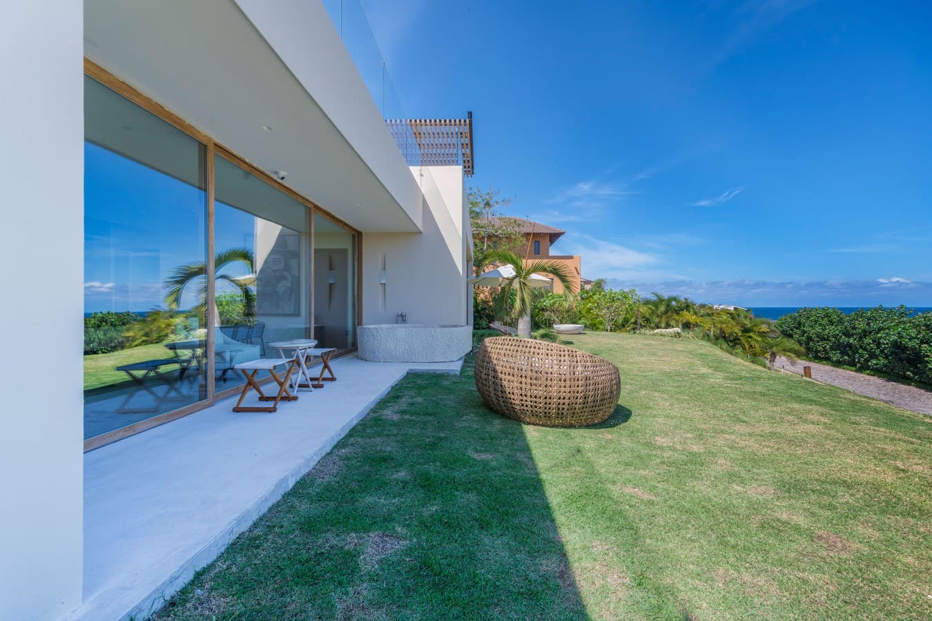 This modern property sits on beautifully manicured grounds with sweeping ocean views, offering a perfect tropical retreat surrounded by lush greenery and clear blue skies.