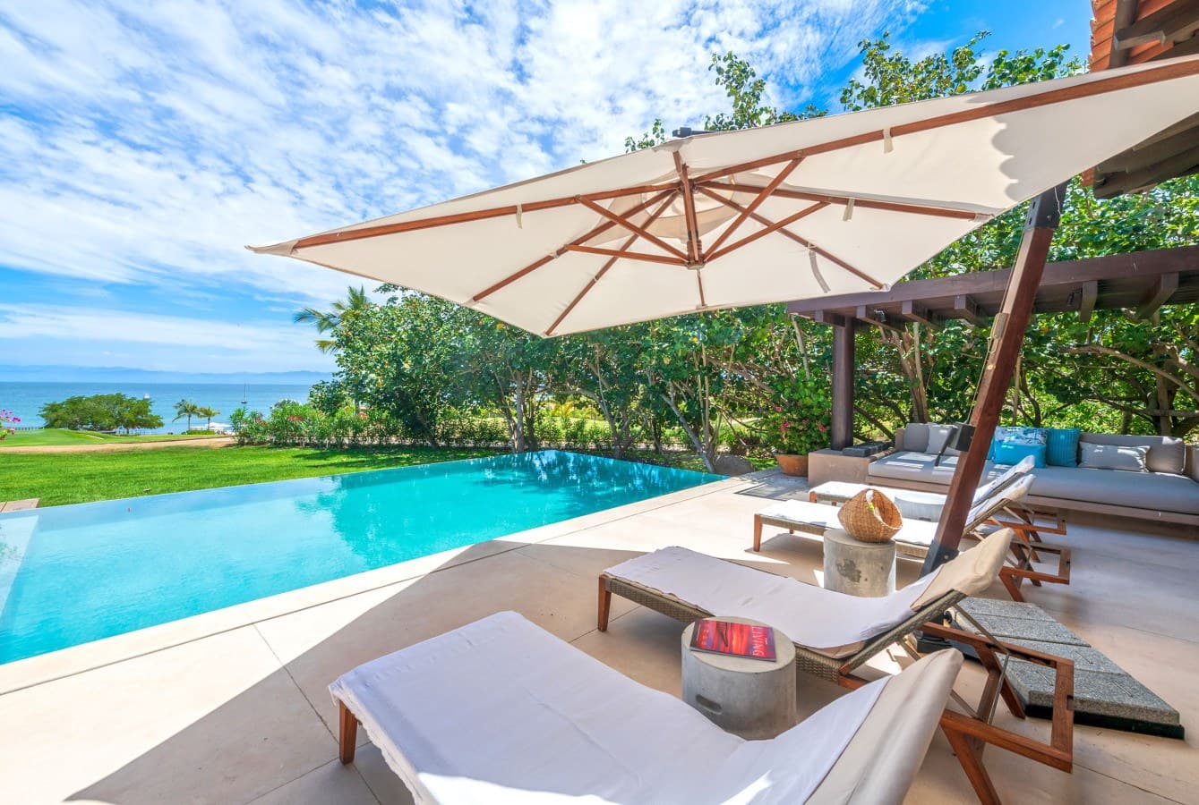 Your private poolside retreat awaits under swaying palms, where turquoise waters meet lush lawns and tranquil ocean views—perfect for sun-soaked relaxation.