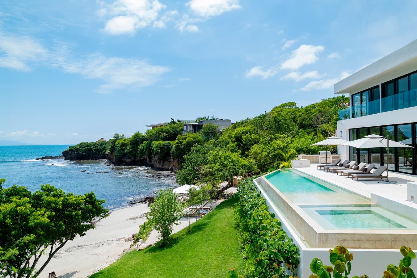 A stunning coastal villa with tiered infinity pools overlooking turquoise waters and a private beach tucked into lush greenery—your perfect tropical escape.