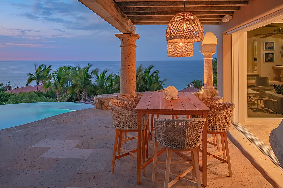 A high table and chairs sits on the patio at sunset.