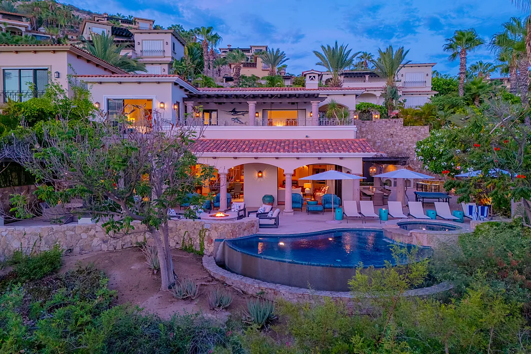 Hillside luxury villa surrounded by lush tropical landscaping with pool, hot tub, and multiple terraces overlooking a prestigious coastal residential neighborhood.