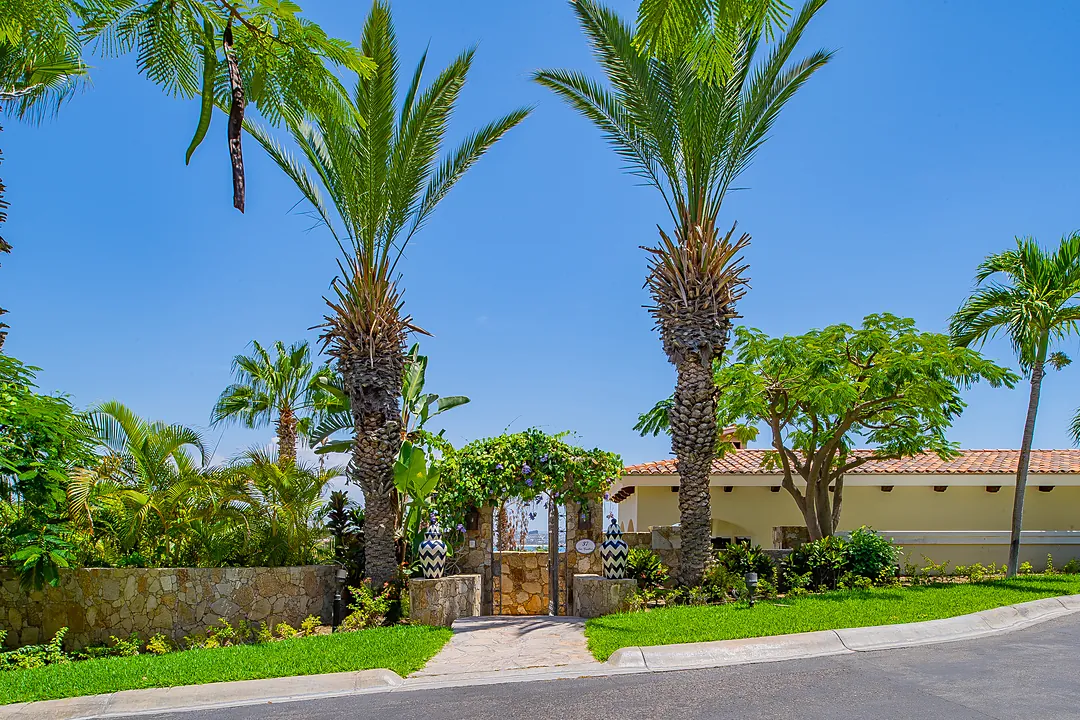 A hacienda-style entrance with arched wooden doors and warm lanterns welcomes you to this elegant coastal retreat, where indoor-outdoor living spaces blend seamlessly into your private patio sanctuary.