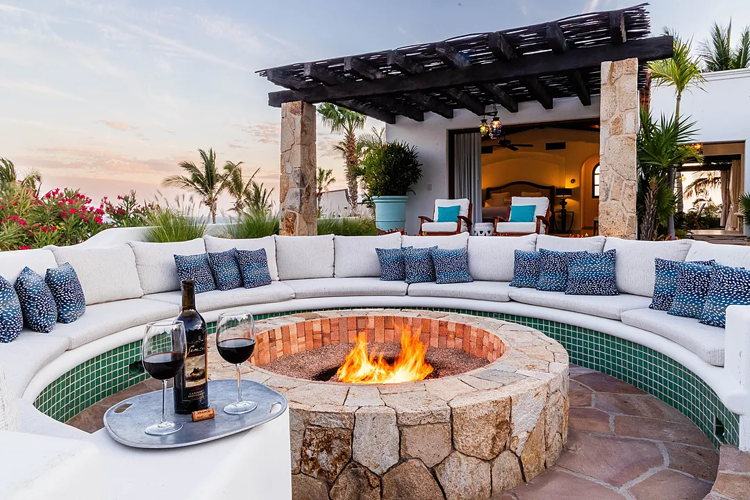 A sunken seating area wraps around a crackling fire pit, inviting you to relax under tropical skies. Turquoise tiles shimmer alongside soft cushions, while lush palms and ocean breezes create your perfect evening retreat.