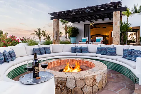 A sunken seating area wraps around a crackling fire pit, inviting you to relax under tropical skies. Turquoise tiles shimmer alongside soft cushions, while lush palms and ocean breezes create your perfect evening retreat.