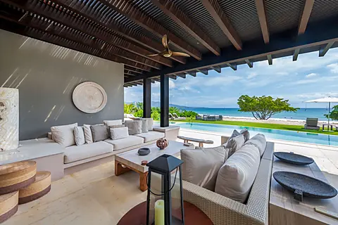 Luxurious beachfront living unfolds before you with plush seating, an infinity pool stretching toward the ocean, and direct beach access just steps away.