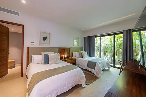 Bedroom 4 · Drift off in your serene twin bedroom, where crisp white linens and lush garden views through floor-to-ceiling windows invite deep relaxation.