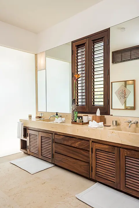 Bathroom 1 (Master ensuite) · Step into your serene private bathroom featuring warm wood cabinetry and elegant stone countertops. Fresh towels and amenities await, while natural light filters through wooden shutters, creating a peaceful space to refresh an