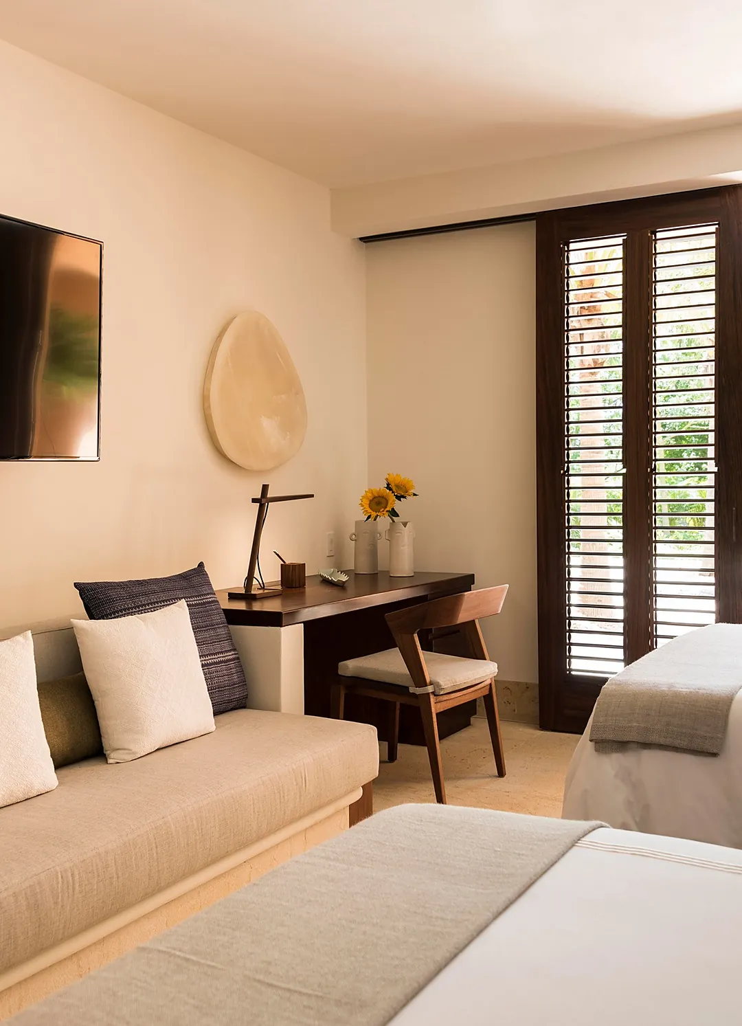 Bedroom 4 · Serene retreat with wooden shutters, cozy seating, and dedicated workspace. Soft earth tones and thoughtful design create the perfect space to relax and recharge.