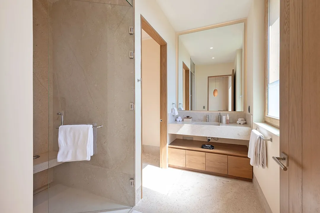 Bathroom 2 · Your private spa-like bathroom features dual sinks set in elegant stone countertops, warm wood storage, and soft ambient lighting that creates a serene retreat after each day's adventures.
