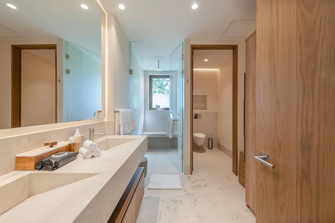 Bathroom 7 · Step into your private bathroom, where clean lines and warm wood tones create a calming retreat. Soft lighting frames the mirror, while plush towels await your use.