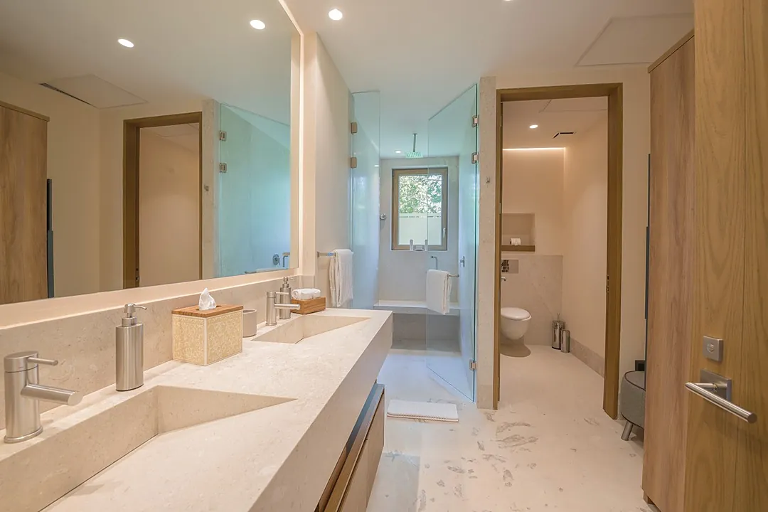 Bathroom 2 · Your private spa-like bathroom features dual sinks set in elegant stone countertops, warm wood storage, and soft ambient lighting that creates a serene retreat after each day's adventures.