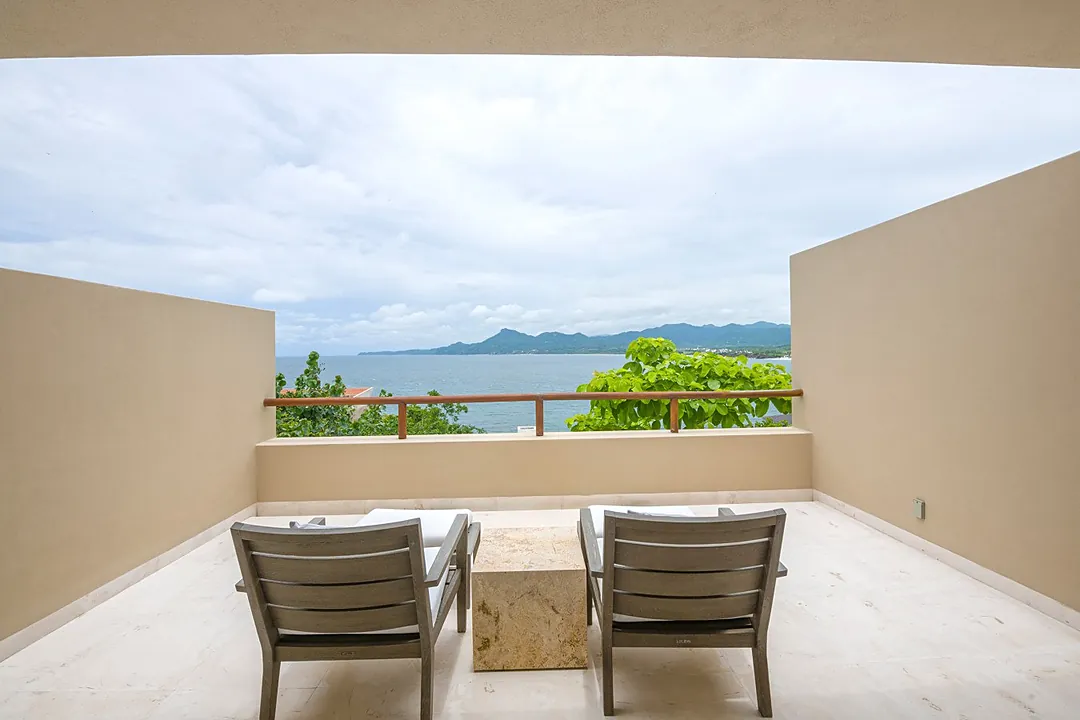 Gather around this stunning dining table while soaking in sweeping ocean and mountain views through floor-to-ceiling glass doors. Your private pool and lush grounds frame the perfect backdrop for unforgettable meals.