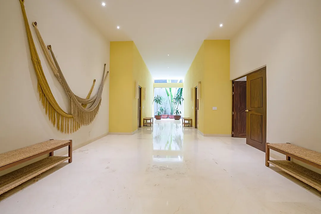 Your spacious, open-plan living room invites relaxation with plush seating and natural textures, seamlessly blending indoor comfort with breathtaking ocean and mountain views just beyond the wide sliding doors.