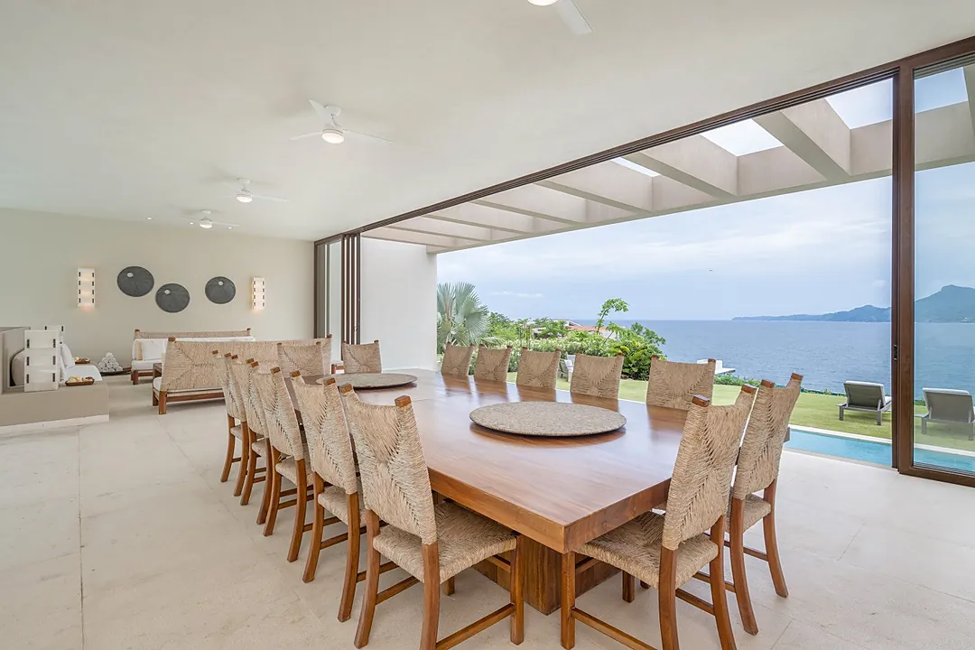 Open-plan living space flows seamlessly onto your private lawn, where tranquil bay waters and mountain silhouettes create a stunning natural backdrop for your stay.