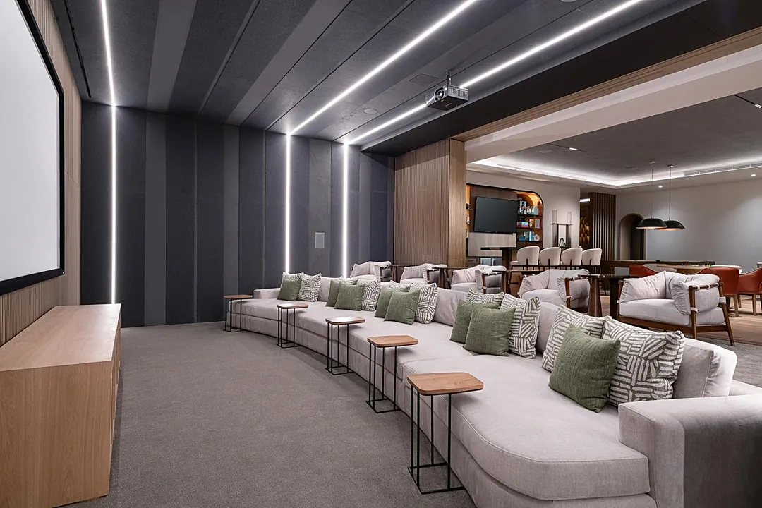 Sleek shared screening room featuring a large projection screen, plush theater-style seating, and modern LED ceiling lighting for the perfect movie night atmosphere.