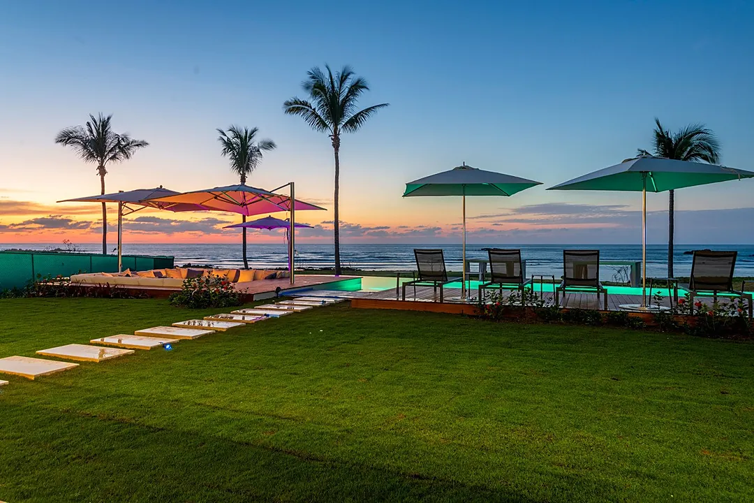 This stunning beachfront property features a sparkling pool, lush tropical landscaping, and breathtaking ocean views, perfect for relaxing evenings under swaying palm trees.