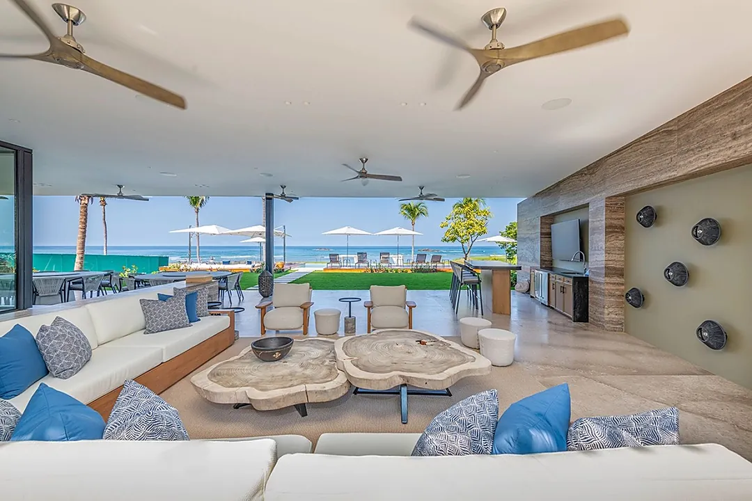 Relax in this breezy open-air lounge where ceiling fans gently cool the space and ocean views unfold before you—unwind on plush seating with tropical waters just steps away.