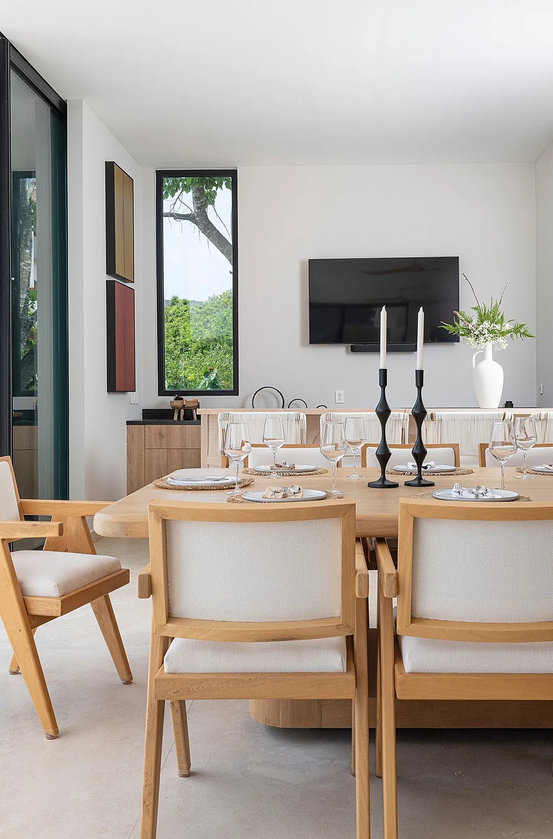 Gather around the elegant dining table, beautifully set and ready for your memorable meals. Natural light streams through tall windows framing lush green views, creating a serene backdrop for lingering conversations.
