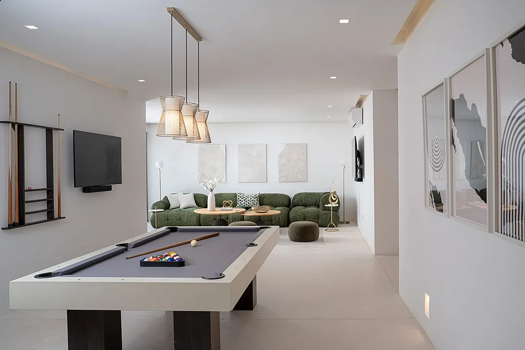 Challenge your friends to a game at the sleek pool table, then sink into the plush green sofa to unwind in your modern entertainment space.