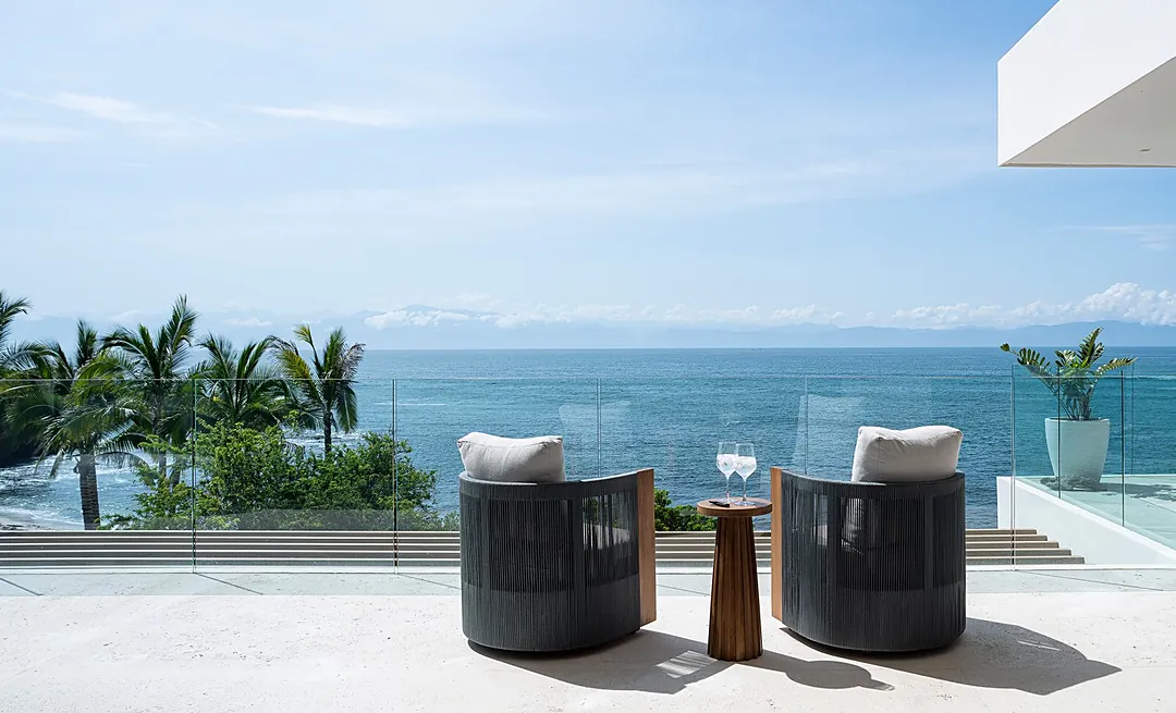 Your private terrace frames panoramic ocean views, where palm-lined shores meet endless blue. Settle into plush seating and savor the tropical breeze as the horizon stretches before you.