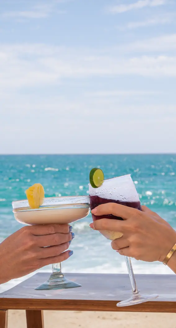 Two guests toasting cocktails by the sea in Los Cabos